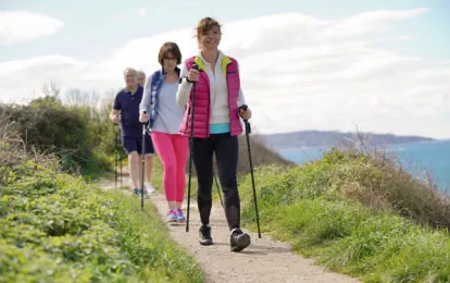 Eine Gruppe von Senioren geht Nordic Walking an der Ostseeküste während ihres Kururlaubs.