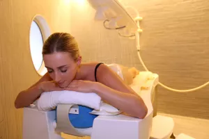 Eine Frau liegt auf einem Tisch und wird von einem Therapeuten mit einer Affusions-Dusche behandelt.