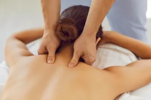 Mädchen erhält eine therapeutische Nackenmassage auf einer Massagecouch in einem Kurort.