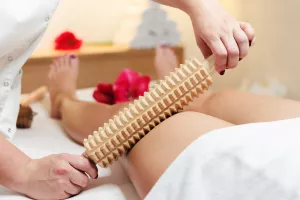 Nahaufnahme einer Frau während einer Anti-Cellulite-Massage im Spa mit einem rollenden Pin oder einer Faszienrolle.