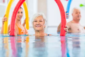 Gruppe von Senioren betreibt Aquafitness im Schwimmbad mit Poolnudeln