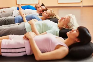 Senior und Gruppe beim autogenen Training zur Entspannung