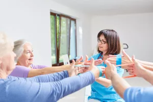 Physiotherapeut führt eine Ergotherapie mit elastischem Band bei Senioren durch.