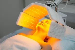 Eine ältere Frau erhält eine Gesichtsverjüngung mit rotem Licht-Behandlung in einem Kurort.