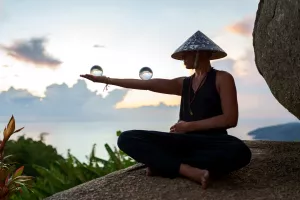 Frau hält bei Sonnenuntergang eine Glaskugel und macht Life Kinetik während ihres Kuraufenthalts