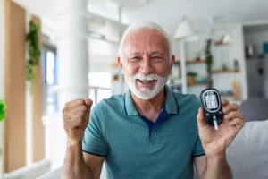 Leitender Mann, der den Blutzuckerspiegel durch Glukometer überprüft und zu Hause den Streifen testet nach einer Kuranwendung der Montignac-Methode