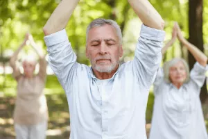 Gelassener reifer Mann beim Praktizieren von Qigong im Park