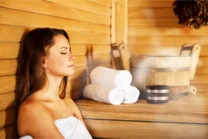 Junge Frau entspannt sich in der Sauna während ihres Wellness-Kuraufenthalts