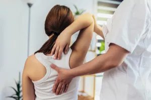 Junge Frau mit chiropraktischer Rückenanpassung und Osteopathie-Schmerztherapie