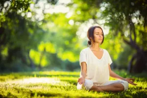 Junge Frau macht Yoga im Park bei Kuraufenthalt