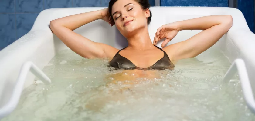 Genießen Sie die wohltuende Wirkung von Thermalwasser bei Ihrem Kururlaub Frau entspannt in einer Badewanne mit Thermalwasser