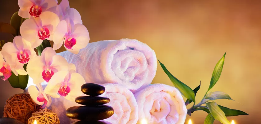Entspannendes Spa-Ambiente mit Massagesteinen und Kerzen Spa-Konzept mit Massagesteinen, Handtüchern und Kerzen auf Naturhintergrund