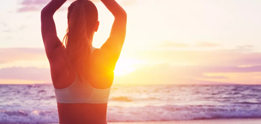 Entspannung durch Yoga am Strand Junge, gesunde Frau praktiziert Yoga am Strand bei Sonnenuntergang